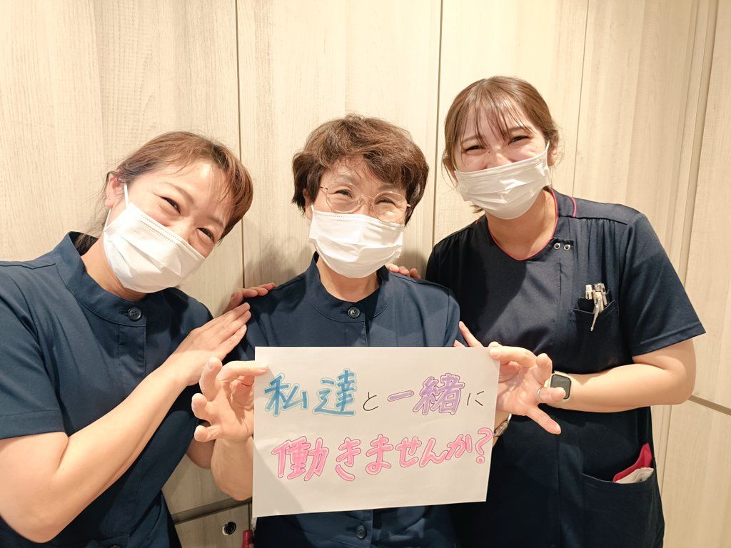 スタッフ3名が「私達と一緒に働きませんか？」と書いたボードを持っている写真